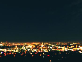 Defocused image of illuminated cityscape against sky at night