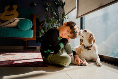 Portrait of cute boy with dog sitting on floor at home