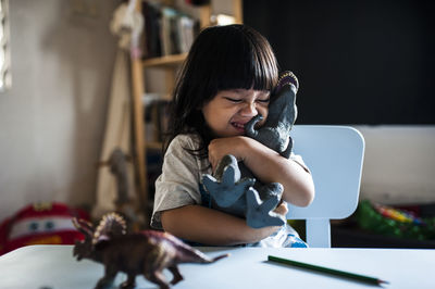 Playful boy embracing toys by table at home