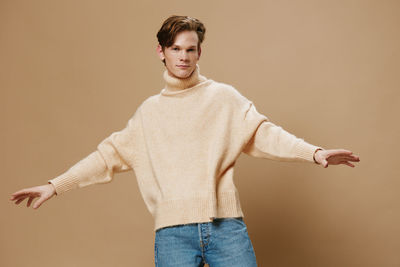 Portrait of young man standing against wall