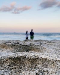 Couple at beach against sky during sunset