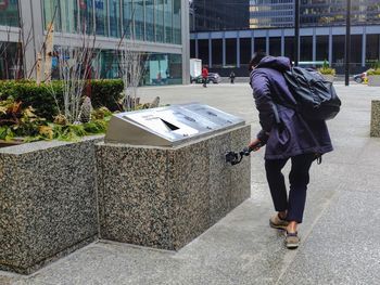 Rear view of woman walking on footpath in city