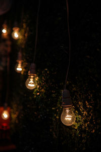 Close-up of illuminated light bulb hanging at night