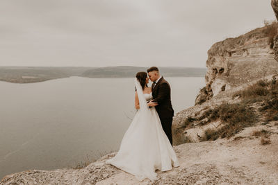 Rear view of bride and bridegroom standing on rock formations