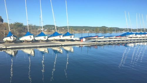 Sailboats moored on sea against clear blue sky