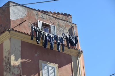 Low angle view of building with laundry against clear sky