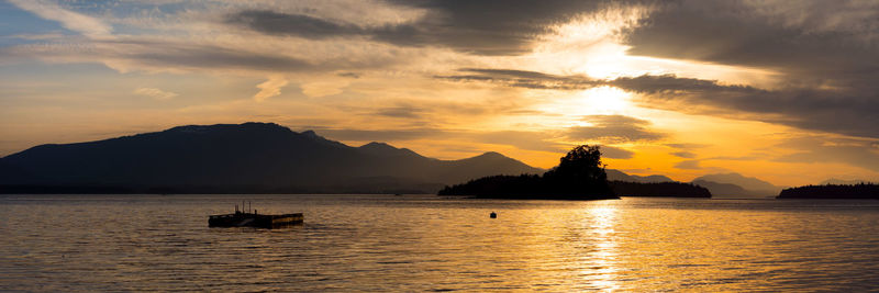 Silhouette boats in sea against sky during sunset