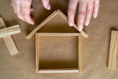 Cropped image of man making wooden figurine house