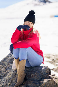 Man sitting on rock at beach during winter