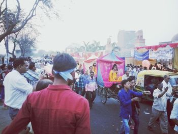 Crowd at music concert in city against sky