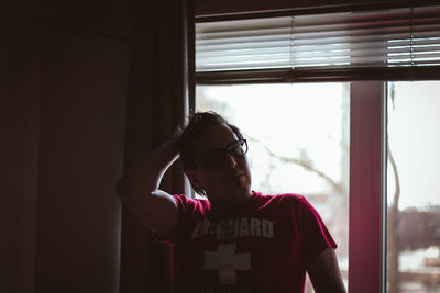 Young woman looking through window