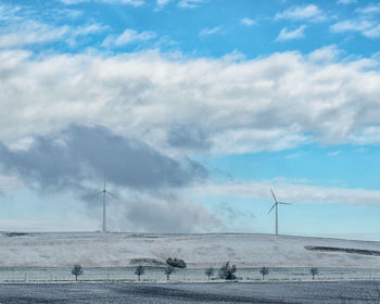 Traditional windmill on field by sea against sky