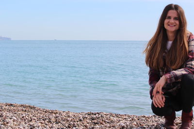 Beautiful young woman on sea shore against sky