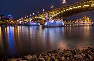 Illuminated bridge over river at night