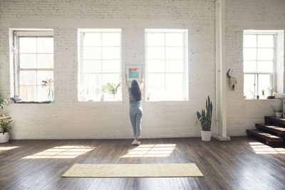 Young woman attaching picture frame to brick wall in a loft