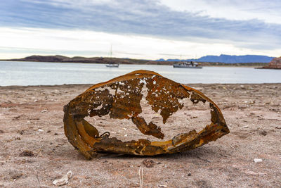 Close-up of rusty metal on beach against sky