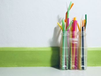 Close-up of colorful drinking straws in bottles on table