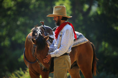 Man wearing costume standing by horse against trees