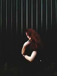 Young woman standing against wall