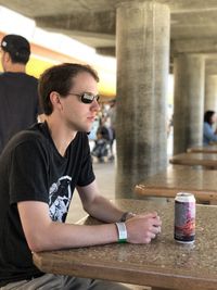 Young man looking down while sitting on table