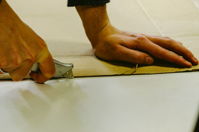 Close-up of man cutting cardboard 