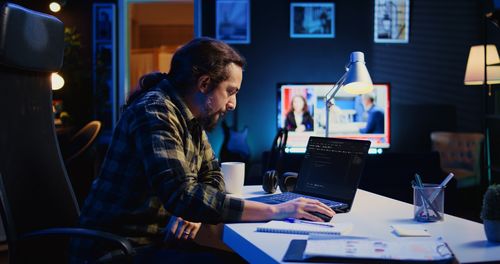 Side view of man using laptop at office