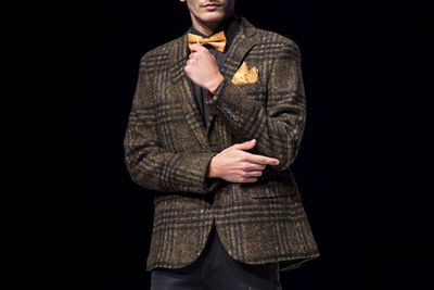 Young man standing against black background