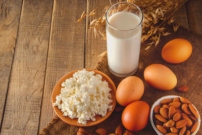 Cottage cheese, eggs, nuts and milk on a wooden background.