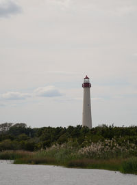 Lighthouse by sea against sky