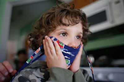 Young boy getting help putting on his mask before leaving his house