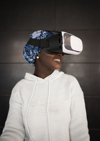 Concentrated young african american female millennial with headscarf in casual clothes pushing button of vr controller while experiencing virtual reality in modern headset