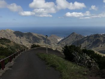 Road leading towards mountains against sky