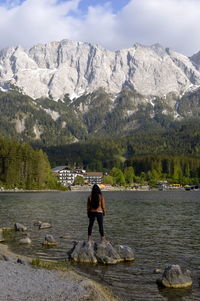 Rear view of man standing on rock by lake