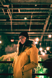 Portrait of woman standing by illuminated light at night