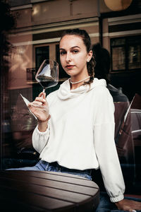 Portrait of young woman holding drink at restaurant