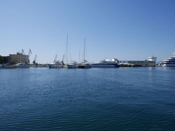 Sailboats sailing in sea against clear blue sky