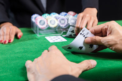 Close-up of people playing poker on table at casino