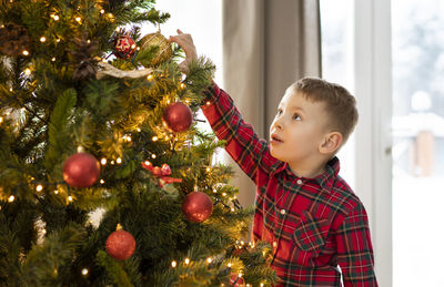 Cute girl decorating christmas tree at home