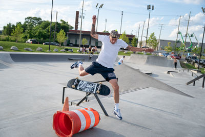 Full length of young man standing on skateboard against sky