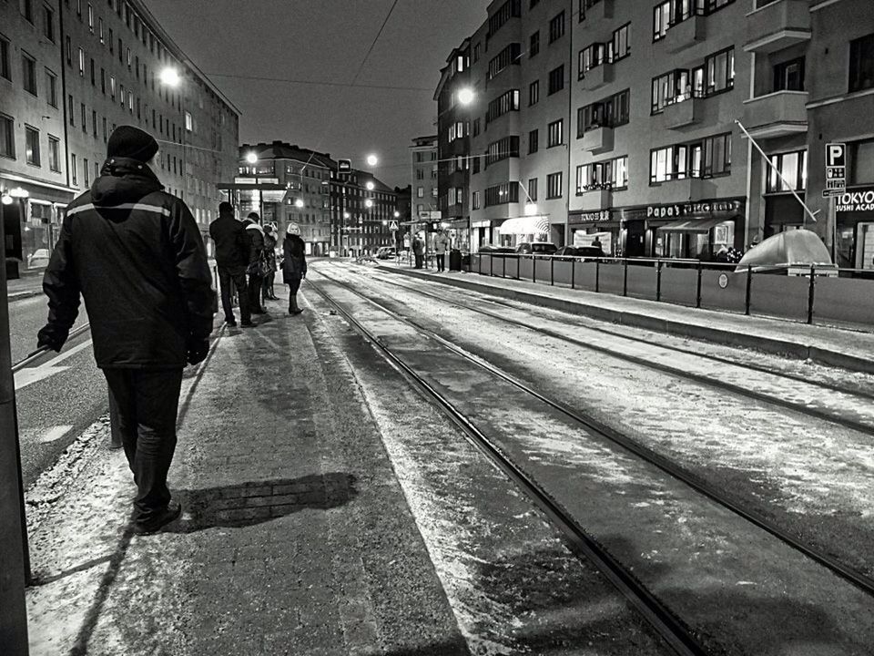 REAR VIEW OF PEOPLE WALKING ON RAILROAD TRACK