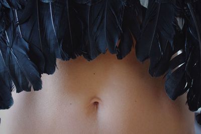 Midsection of young woman wearing black feather costume