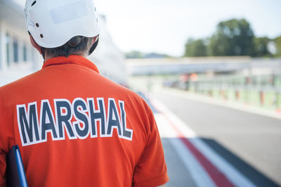 Rear view of motorsport marshal standing at pit stop