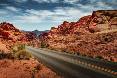 Road leading towards mountains against sky