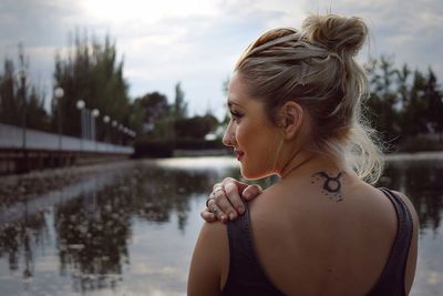 Rear view of young woman standing by lake