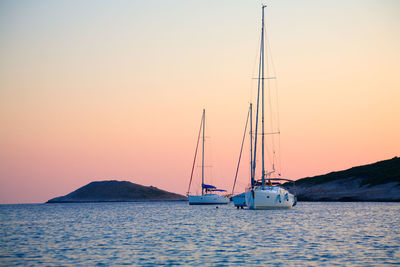 Sailboat sailing on sea against clear sky during sunset