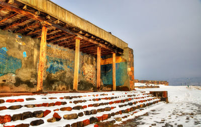 Built structure on snow covered field against sky