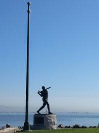 Statue on beach against clear blue sky