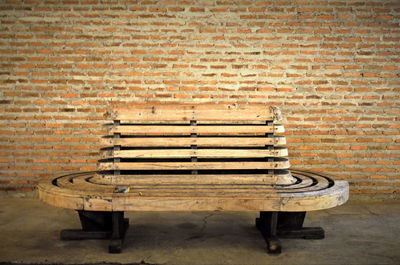 Empty bench against brick wall