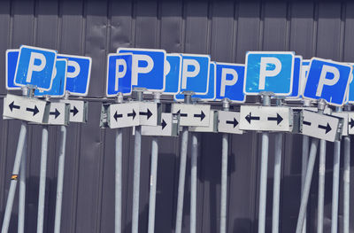 Parking signs standi against blue wall