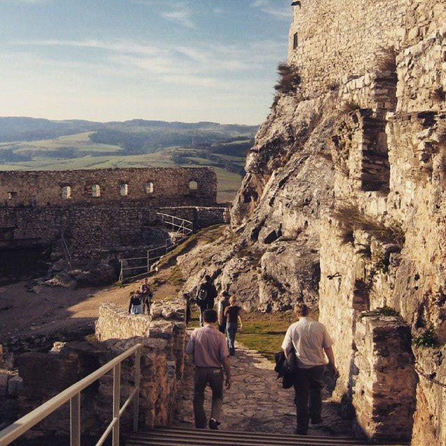 men, built structure, architecture, lifestyles, person, leisure activity, rear view, mountain, full length, sky, building exterior, walking, tourist, casual clothing, travel, tourism, history, rock - object